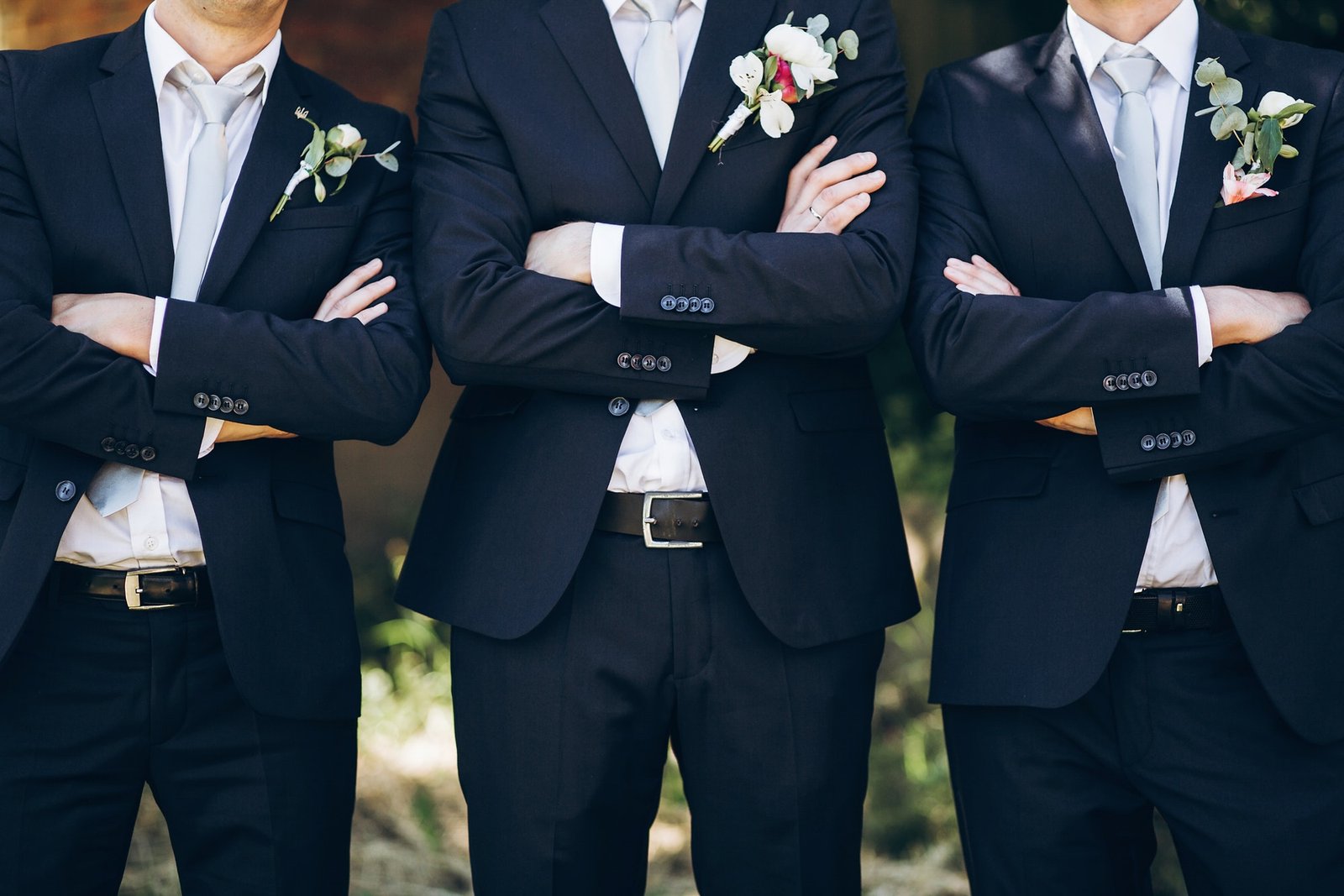 stylish-groom-in-suit-posing-with-groomsmen-in-garden-on-wedding-day.jpg